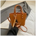 Gros plan du sac seau marron tissé avec breloque en bois et détails de la bandoulière - Avec Pendentif / Marron