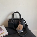 Detail of black Boston bag with mini pouch and cute plush dog charm on a soft cushion - With Charm / Black