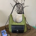 Sac vintage en daim vert et noir avec poche en cuir posé sur une table en bois - Vert