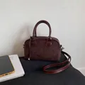 Dark brown suede Boston bag with leather handles and crossbody strap on a soft cushion - Brown