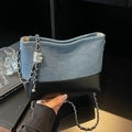 Bucket Bag aus Denim und schwarzem Leder mit silbernem Kettenriemen in der Hand - Schwarz