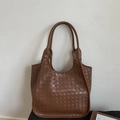 Detailed view of the brown woven leather tote bag featuring Intrecciato texture and design - Brown