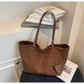 Detail of deep brown suede tote bag with leather handle and matching decorative charm - Brown
