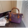 Detail of purple nylon bucket bag with leather handles shown in a lifestyle office setting - Purple