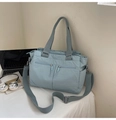 Detail of light blue nylon tote bag showing multiple zipper pockets and adjustable strap - Blue