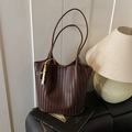 Dunkelbraune handgewebte Leder-Tote-Bag mit stilvollem Perlenanhänger auf Regal - Kaffee mit Anhänger