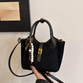 Black suede bucket bag with gold buckle and beaded charm in a handheld view - With Charm / Black