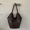 Detail einer dunkelbraunen Tragetasche mit glatter Textur, Doppelgurten und kleiner Tasche - Braun