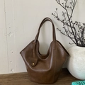 Detailed view of dark brown leather tote bag with unique curved opening and mini charm pouch - Brown