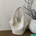 Detailed view of cream white leather bucket bag with gold stud accent on dark wood surface - Off White