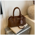 Close-up of retro brown frosted suede handbag placed on art books and vintage suitcase - Brown