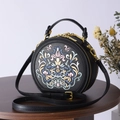 Detailed close-up of intricate floral embroidery on black leather round crossbody bag - Black