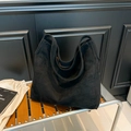 Minimalist large black faux suede tote bag with wide shoulder strap on wooden bench - Black