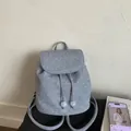 Detail eines hellblauen Vintage-Rucksacks mit Kordelzugverschluss und Klappdeckel - Denim-Blau