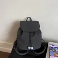 Detail eines dunkelgrauen Segeltuchrucksacks mit Kordelzug und blauen Perlenakzenten - Schwarz