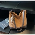 Detail of a brown suede hobo bag with leather base and plush pendant on wood - With Pendant / Khaki