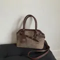 Detalle de bolso bandolera de ante marrón con hebilla vintage y etiqueta de marca - café