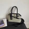 Detalle de bolso de lona beige con ribete de cuero negro, hebilla de metal y correa - Caqui