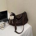 Dark brown leather dumpling bag with chain strap and bear charm on office desk - Coffee