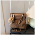 Détail du sac à dos marron en daim avec logo embossé et charmant pendentif ours - Marron avec pendentif