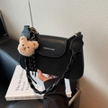 Schwarze matte Schultertasche mit weißem Schriftzug und braunem Plüschbär-Anhänger - Schwarz