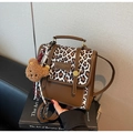 Detail der braunen Ledertasche mit Leopardenmuster-Klappe und süßem Plüschbär-Anhänger - Cremeweiß Mit Anhänger