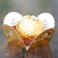 Macro shot of laser-cut gold rose paper liner with chocolate on dark wood surface - Reflective Gold