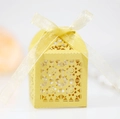 Nahaufnahme der gelben, lasergeschnittenen Bonbonschachtel mit Blumenmuster und Schleife - Gold
