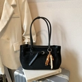 Bolso tote negro de ante con colgante de cuentas de madera sobre maleta plateada - Negro