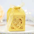 Nahaufnahme des gelben Hochzeits-Geschenkkartons mit Laser-Herz-Muster und Seidenband - Gold