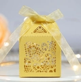 Detail of yellow laser-cut ivory favor box with elegant floral patterns and gold ribbon - Gold