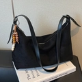 Borsa hobo nera in pelle scamosciata con ciondolo etnico su sfondo libro - Con Ciondolo / Nero