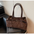 Détail d'un sac cabas marron foncé en daim avec boucle métallique et longue bandoulière - café