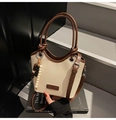 Détail du sac seau en toile montrant le logo en cuir et le pompon en perles de bois - Blanc avec pendentif