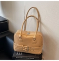 Dettaglio borsa Boston vintage crema con fibbie Y2K esposta su alcuni libri - Cachi