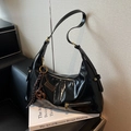 Glänzende schwarze Schultertasche mit goldener Hardware und braunem Anhänger - Schwarz mit Anhänger