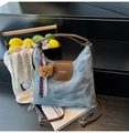 Detail of blue denim tote bag with brown leather accents and a plush bear pendant - With Charm / Denim Blue