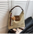 Macro shot of khaki green hobo bag featuring dark brown leather straps and plush bear charm - With Charm / Off White