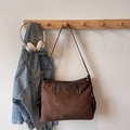 Detail of dark brown faux suede hobo bag featuring metal logo and side pocket on wooden hook - Coffee without Pendant
