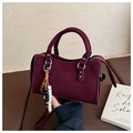 Detail of burgundy suede handbag featuring wavy edges and colorful bead bag charm accessory - Red with Pendant