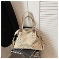 Detail of vintage beige tote bag with rivets placed on a silver suitcase for travel - Green