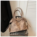 Detail of vintage brown tote bag with V-shaped silver rivets and textured leather finish - Brown