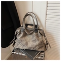 Detail of vintage matte grey tote bag with stud accents placed on a metal suitcase - Black