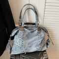 Distressed grey-blue tote bag with V-shaped metal studs on a silver suitcase - Blue