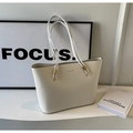 Detalle de bolso tote de cuero crema con logotipo dorado y correas de hombro elegantes - Blanco Roto