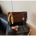 Détail du sac seau en daim marron avec surpiqûres losanges et breloque pompon en bois - Café avec Pendentif