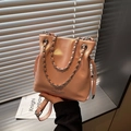 Chic cherry pink leather bucket bag with silver chain strap shown in natural light - Pink