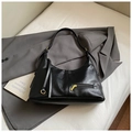Detail der schwarzen Tote-Bag aus genarbtem Leder mit goldener Hardware auf Anzug - Biker-Schwarz