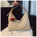 Detail der matten cremefarbenen Hobo-Tasche mit MERFIL-Logo-Prägung und farbenfrohem Anhänger - Cremeweiß