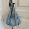 Detail view of large sky blue suede hobo bag hanging on a white door handle - Blue